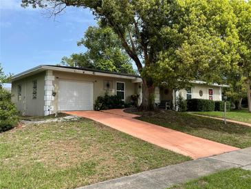 Charming one story home featuring a two-car garage, lush landscaping, and mature trees at 1310 Briarwood Ave, Deltona, FL 32725