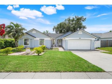 Charming single-story home with well-manicured lawn, lush landscaping and a two-car garage at 1322 Ravida Woods Dr, Apopka, FL 32703
