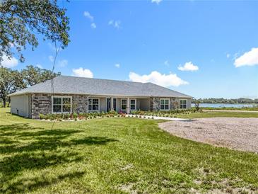 Charming exterior with stone accents, manicured lawn, and a view of the water at 14243 County Road 450, Umatilla, FL 32784