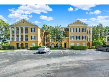 Three story tan condo building with black shutters, white columns, and landscaping in a parking lot at 3757 Conroy Rd # 2525, Orlando, FL 32839