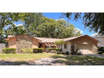 Charming single-story home featuring stone accents, mature landscaping, and an attached two-car garage at 8547 Cedar Cove Dr, Orlando, FL 32819