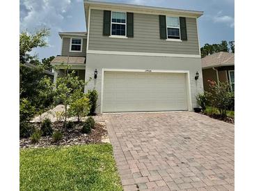 Charming two-story home featuring a two-car garage and a well-manicured front yard with brick-paved driveway at 17426 Saw Palmetto Ave, Clermont, FL 34714