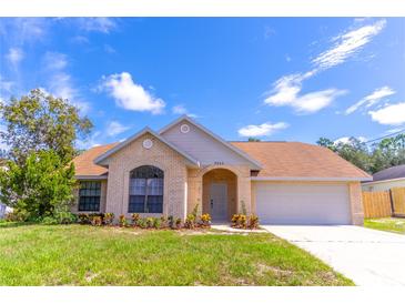 Charming single-story home with a brick facade, arched entryway, manicured lawn, and attached two car garage at 2444 Omaha Dr, Deltona, FL 32738