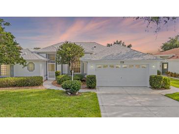 Charming single-story home with a well-manicured lawn and beautiful landscaping, featuring a two-car garage at 26908 Honeymoon Ave, Leesburg, FL 34748