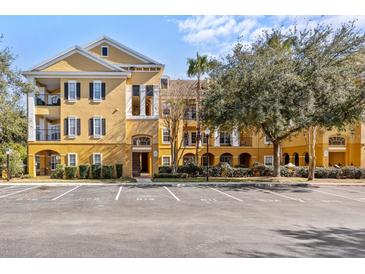 Inviting yellow condo building featuring black shutters, balconies, and well-manicured landscaping at 3707 Conroy Rd # 1715, Orlando, FL 32839