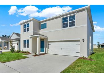Charming two-story home featuring a two-car garage, blue door, and well-maintained landscaping at 5135 Marshelder St, Apopka, FL 32712