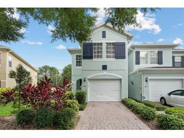 Inviting two-story townhome with a brick driveway, attached garage, and lush landscaping at 6027 Strada Isle Way, Orlando, FL 32835