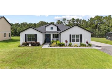 Charming single-story farmhouse with green lawn, blue door, black shutters and manicured landscaping at 7191 Old Melbourne Hwy, St Cloud, FL 34771