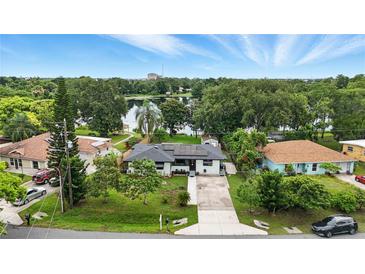Charming single-story home features solar panels, a long driveway, and lovely landscaping with a lake view at 2154 Lake Christie Dr, Orlando, FL 32809