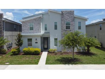 Charming two-story home featuring modern design with stone accents and well-manicured landscaping at 2855 Bookmark Dr, Kissimmee, FL 34746