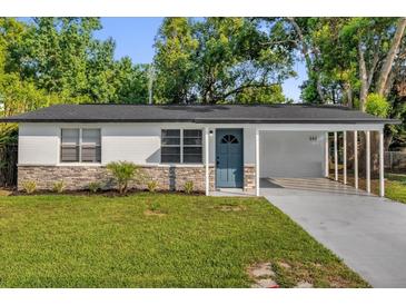 Charming home featuring stone accents, a blue front door, and a well-manicured lawn at 461 Brentwood Dr, Daytona Beach, FL 32117