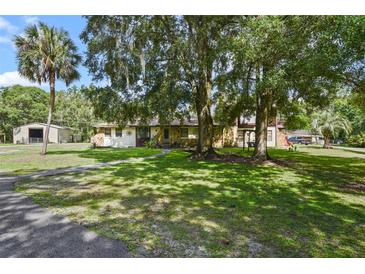 Charming home featuring a stone facade, mature trees, and a lush, green lawn at 546 Winona Dr, Geneva, FL 32732