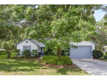 Charming single-story home with a well-maintained lawn, mature trees, and a two-car garage at 5990 Se 5Th Pl, Ocala, FL 34472