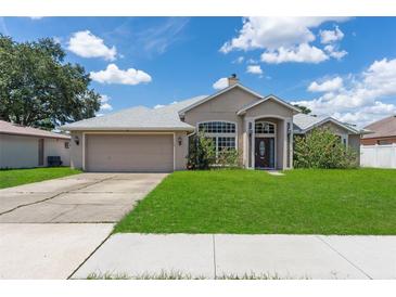 Charming single-story home featuring a manicured lawn, arched entryway, and an attached two-car garage at 1154 Feather Dr, Deltona, FL 32725