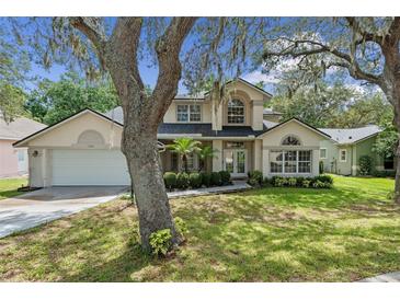 Charming home featuring a well-maintained lawn, mature trees, and a two-car garage, complete with inviting curb appeal at 1225 Hollow Pine Dr, Oviedo, FL 32765