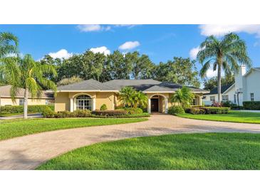 Charming single-story home featuring a circular brick driveway and lush, tropical landscaping at 1455 Royal Forest Loop, Lakeland, FL 33811