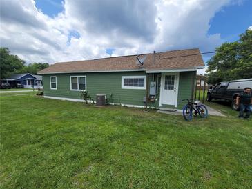 Green home exterior with a well maintained lawn and blue bicycle parked near the entrance at 1519 Illinois Ave, St Cloud, FL 34769