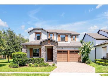 Charming two-story home featuring stone accents, a paved driveway, and a well-manicured lawn at 6925 Trellis Vine Loop, Windermere, FL 34786