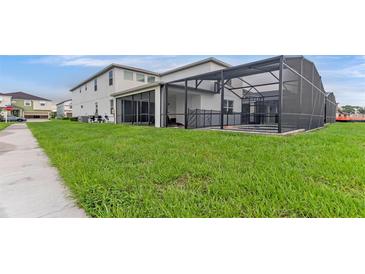 Expansive backyard featuring a screen-enclosed pool area, lush lawn, and ample space for activities at 2114 Fleming Mist Pl, Kissimmee, FL 34747