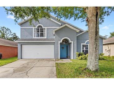 Charming two-story home with a two-car garage, blue door, and well-maintained lawn at 38 Jett Loop, Apopka, FL 32712