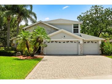 Charming two-story home with three-car garage, manicured landscaping, and a brick paver driveway at 901 Grovesmere Loop, Ocoee, FL 34761