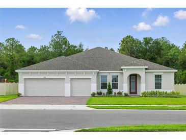 Charming single-story home featuring a three-car garage and manicured lawn at 5204 Obsidian Gate Dr, Mount Dora, FL 32757