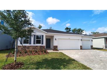 Charming single-story home with a manicured lawn, brick accents, and a three-car garage at 1323 Wood Line Dr, Deland, FL 32720
