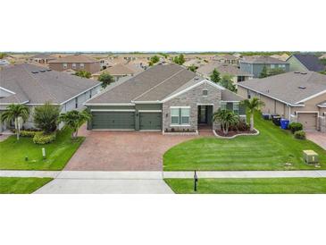Charming single-story home featuring a three-car garage, brick paved driveway, and well-manicured lawn at 1556 Alligator St, St Cloud, FL 34771