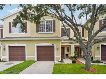 Charming townhome with a well-manicured lawn, brown shutters and a two-car garage at 1967 Beacon Bay Ct, Apopka, FL 32712