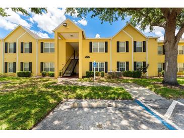Inviting condo featuring a yellow facade, black shutters, and mature trees at 2041 Dixie Belle Dr # 2041C, Orlando, FL 32812