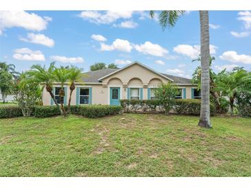 Inviting single story home featuring a well-manicured lawn, mature landscaping, and a charming blue front door at 2042 Hayfield Way, Apopka, FL 32712