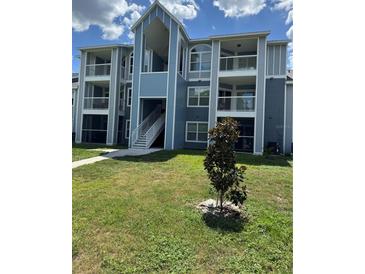 Multi-level condominium building with balconies and blue exterior paint and well-manicured lawn at 2592 Grassy Point Dr # 306, Lake Mary, FL 32746
