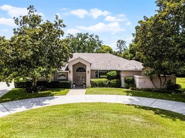 Charming single-story home featuring circular driveway, mature trees, and manicured landscaping at 707 Heritage Ne Dr, Winter Haven, FL 33881