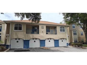 Charming condo building exterior with tan stucco, blue accents, and private balconies over garages at 7220 Westpointe Blvd # 1429, Orlando, FL 32835
