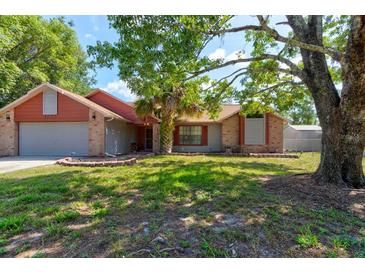 Charming single-story home featuring a brick facade, mature trees, and a well-maintained lawn at 3237 Newmark Dr, Deltona, FL 32738