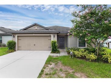 Charming single-story home featuring a two-car garage and beautifully landscaped front yard with flowering tree at 340 Pheasant Dr, Haines City, FL 33844
