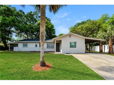 Charming single-story home with a well-manicured lawn, carport, and lovely front yard tree at 4 Kasey Dr, Orlando, FL 32807