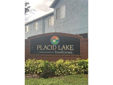 Placid Lake Townhomes brick sign with colorful lotus flower logo surrounded by greenery at 454 Wilton Cir, Sanford, FL 32773