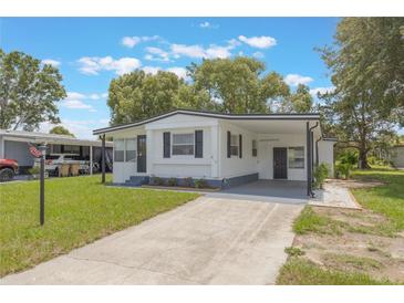 Charming single-story home with a carport and well-maintained front lawn in a quiet community at 814 Roseapple Ave, Lady Lake, FL 32159
