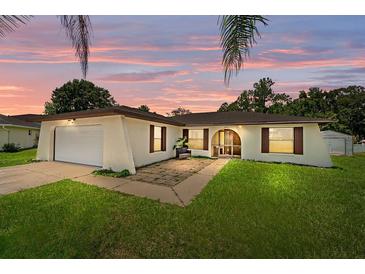 Charming single-story home with a well-manicured lawn, lovely sunset and attached garage at 909 Hendon Place, Kissimmee, FL 34758
