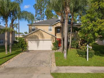 Two-story home featuring a two-car garage, red front door, and lush landscaping with mature palm trees at 1130 Burland Cir, Winter Garden, FL 34787