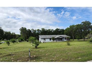 Charming single story home with a large front yard, mature trees, and beautiful landscaping at 13208 Massachusetts Ave, Astatula, FL 34705