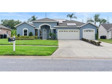 Charming blue home featuring a well-manicured lawn, two-car garage, and freshly painted driveway at 4110 Maplegrove Dr, Orlando, FL 32818