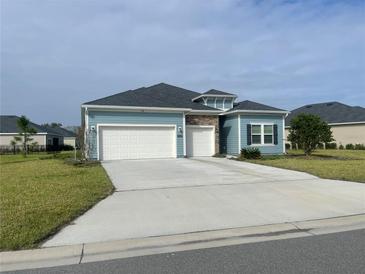 Charming single-Gathering home featuring blue siding, a stone accent, and a two-car garage at 4167 Clifden Dr, Ormond Beach, FL 32174