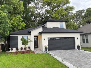 Contemporary home features a black roof, a two-car garage, and a beautifully landscaped front yard at 1526 Hempel Ave, Gotha, FL 34734