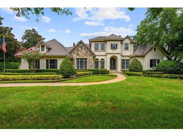 Stunning two-story home with a lush green lawn, manicured landscaping, and stone accents at 6138 Greatwater Dr, Windermere, FL 34786