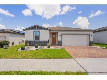 Charming single-Gathering home with a well-manicured lawn, brick driveway, and a two-car garage at 840 Teton St, Haines City, FL 33844
