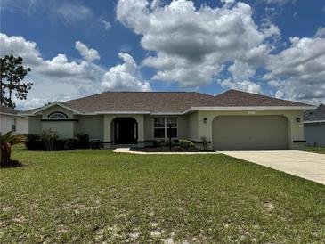 Charming one-story home with a well-manicured lawn and attached two-car garage on a sunny day at 8414 Sw 136Th Pl, Ocala, FL 34473