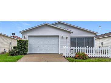 Charming single story home with manicured lawn, white picket fence, attached two car garage, and attractive landscaping at 9376 Se 175Th Pompion St, The Villages, FL 32162