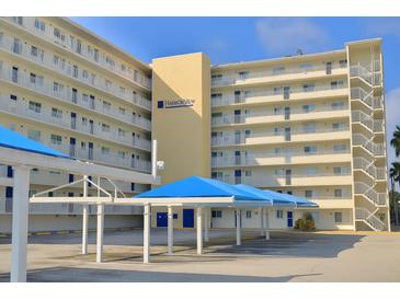 Harborview building with balconies and covered parking with blue canvas, set against a clear blue sky at 145 N Halifax Ave # 705, Daytona Beach, FL 32118